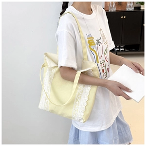 Détail du sac cabas en toile jaune clair avec dentelle blanche et bandoulières solides