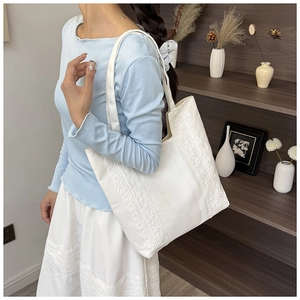 Détail d'un sac cabas en toile avec bordure en dentelle blanche et longues bandoulières