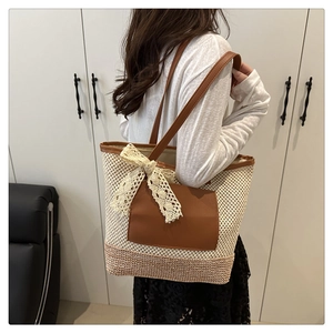 Detail of a woven straw tote with leather straps and a decorative white lace bow