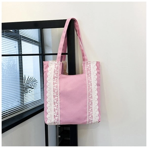 Détail d'un cabas en toile rose avec bordure en dentelle blanche et couture latérale