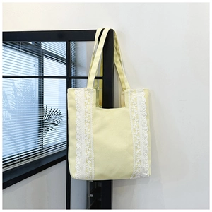 Détail du sac cabas en toile jaune avec bordure en dentelle blanche et bandoulières