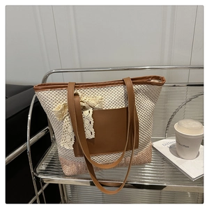 Detail of woven straw tote bag with brown leather straps and lace bow decoration