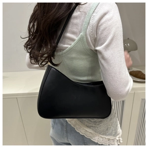 Minimalist black crescent shoulder bag shown on model for sleek 2025 spring casual style
