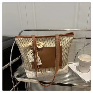 Detail of straw woven tote bag featuring brown leather trim and lace bow decoration