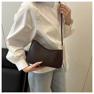 Detail view of a minimalist dark brown crescent shoulder bag with golden hardware