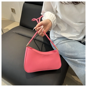Detailed shot of a pink leather crescent underarm bag with gold metal buckle accents