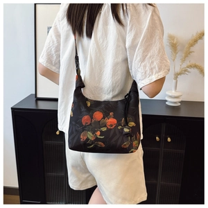Detail of crescent crossbody bag with orange persimmon print and adjustable strap