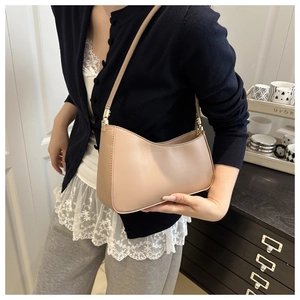 Detail of minimalist beige faux leather underarm bag featuring elegant golden ring strap