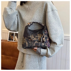 Detail of vintage floral pattern and black buckle closure on a chic crossbody bag