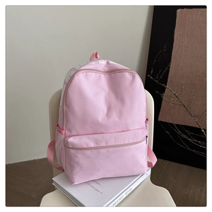 Pink nylon backpack featuring side mesh pockets and front zip storage on a white chair