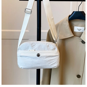 Detail of off-white nylon crossbody bag with pleated texture and wide shoulder strap