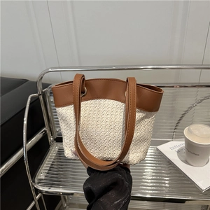 Large woven beach tote bag with brown leather trim held in a modern setting