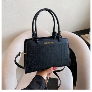 Close-up of black crocodile pattern leather handbag with gold Fashion Bag logo