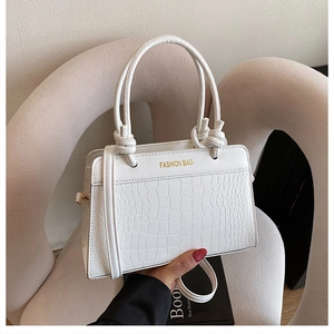 Detail view of white handbag with crocodile texture and golden Fashion Bag lettering