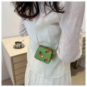 Close-up of green cherry print wallet with gold snap button and metal chain strap