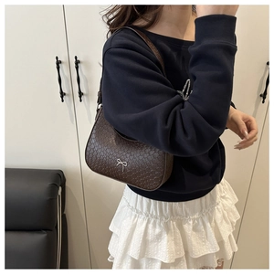 Detail of dark brown mock croc underarm bag with silver bow accent on shoulder