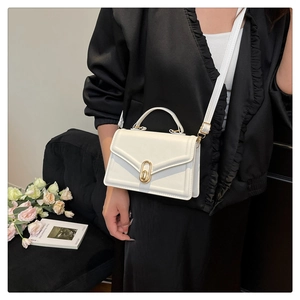 Detailed close-up of a white mini leather handbag with golden oval clasp and top handle