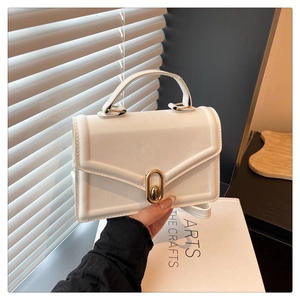 Detailed shot of white faux leather crossbody bag with elegant gold oval twist lock