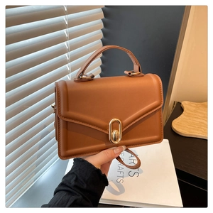 Détail du sac en similicuir caramel avec fermoir ovale doré et texture mate élégante