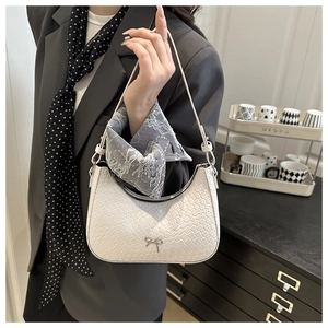 Detail of woven texture underarm bag with metal bow and white lace scarf decor