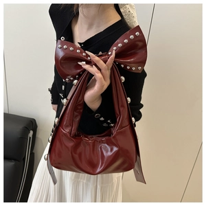 Detail of burgundy crescent bag with large bow and silver metal rivets decoration
