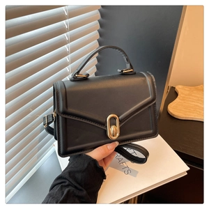 Détail d'un sac bandoulière minimaliste en cuir noir avec un fermoir rotatif doré élégant
