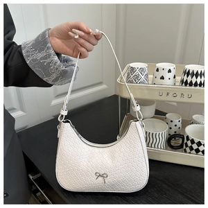 Detail of cream woven shoulder bag with small metal bow and PU leather strap