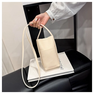 Detail of beige lychee grain leather mini bucket bag with handle and crossbody strap
