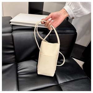 Detalle del mini bolso cubo crema con textura de lichi y correa delgada elegante