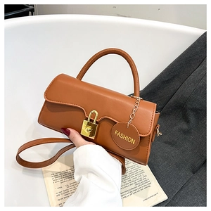 Brown leather handbag with gold clasp and Fashion tag shown in lifestyle context
