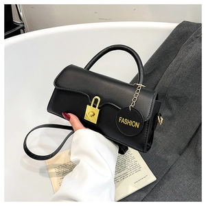 Detail of black leather handbag featuring a gold padlock clasp and fashion charm tag