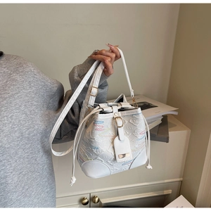 Dettaglio della borsa a secchiello bianca con ricamo arcobaleno e finiture dorate