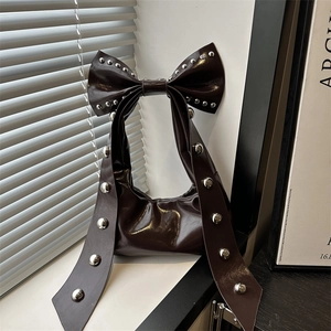 Dark brown high-gloss underarm bag with large bow and silver studs on top handle