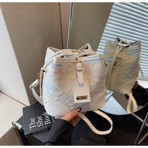 Dettaglio della goffratura floreale e ricamo a onde colorate sulla borsa a secchiello bianca