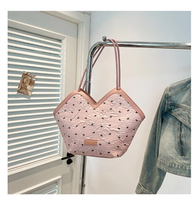 Close-up of a pink textured shoulder bag with bow patterns hanging on a metal garment rack