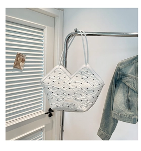 Detail of white tote bag with black bows and pleated texture hanging on a silver stand