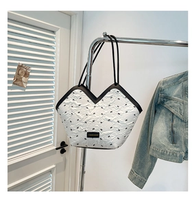 Detail of white quilted tote with black bow embroidery and V-shaped opening design
