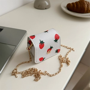 Mini white PU leather wallet with strawberry print and gold chain strap on a desk