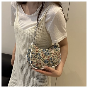Détail du sac jacquard floral avec nœud en métal et bandoulière en chaîne argentée