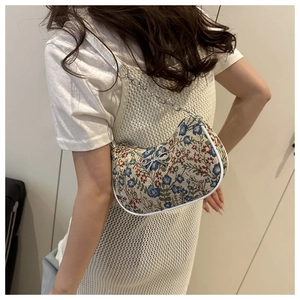 Détail d'un sac porté épaule en jacquard floral avec nœud métallique et chaîne argentée
