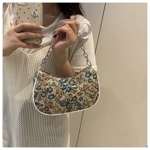 Gros plan sur la broderie florale et le nœud argenté du sac à bandoulière avec chaîne