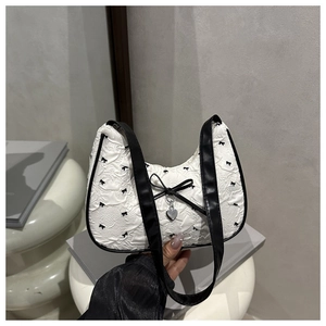 Close-up of textured fabric with bow patterns and silver heart charm on a stylish handbag