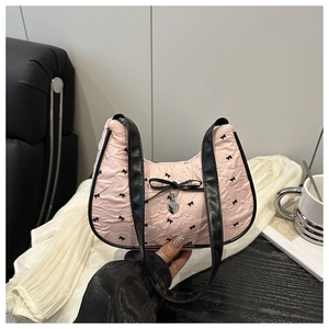 Close-up of pink textured crescent bag with black bow prints and silver heart charm