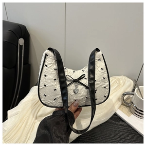 Detail of white crescent bag with black bow prints and silver heart pendant charm