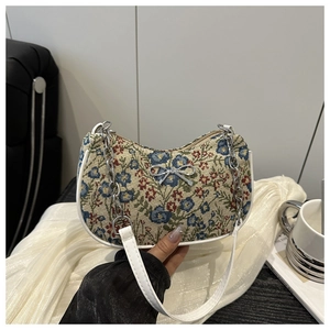 Détail du tissu jacquard floral avec nœud argenté et bandoulière en chaîne sur le sac