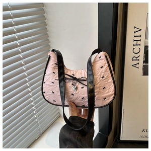 Detailed close-up of pink seersucker bag with black bow print and silver heart charm