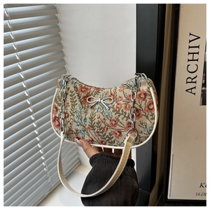 Détail du sac lune en tapisserie florale avec nœud métallique et chaîne argentée