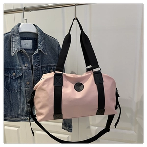 Detail of light pink barrel duffel bag hanging with black straps and adjustable buckle