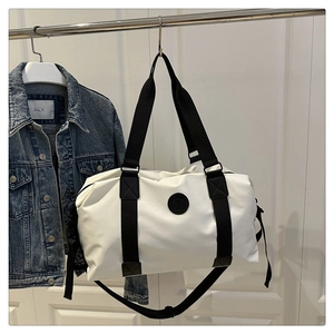 Close-up of a white Oxford travel bag with black straps and adjustable shoulder strap