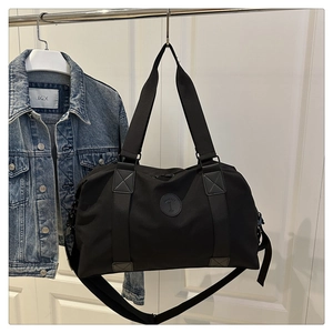 Close-up of black versatile duffel bag with a leather logo and adjustable shoulder strap